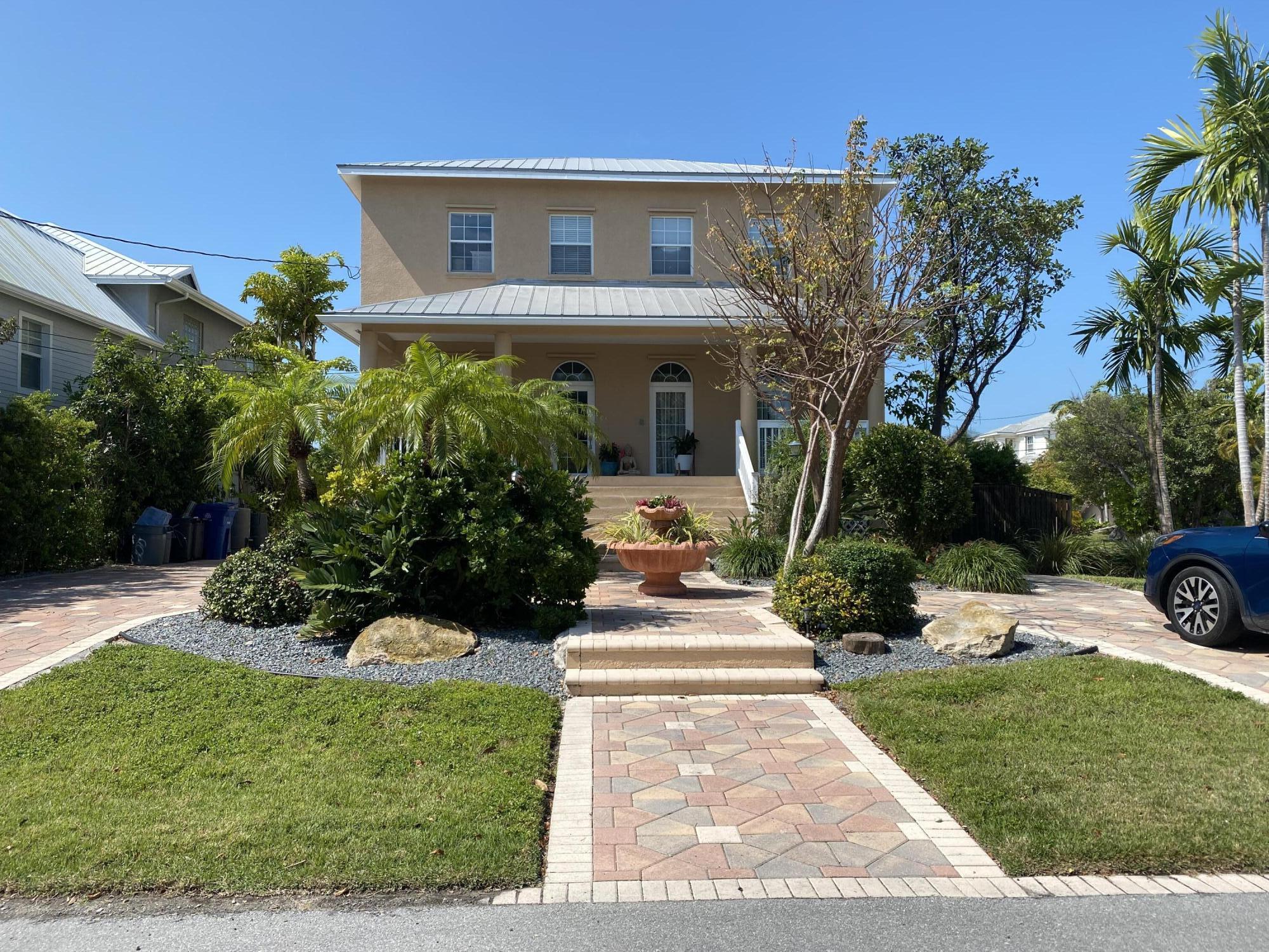 a front view of a house with a yard and potted plants