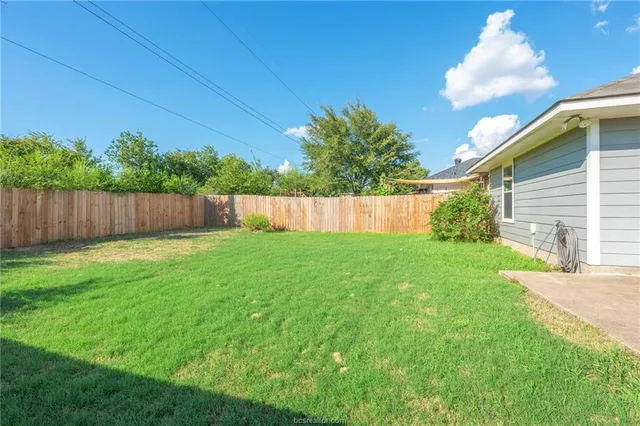 a view of a backyard with potted plants and wooden fence