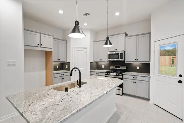 a kitchen with stainless steel appliances granite countertop a sink a stove and a refrigerator