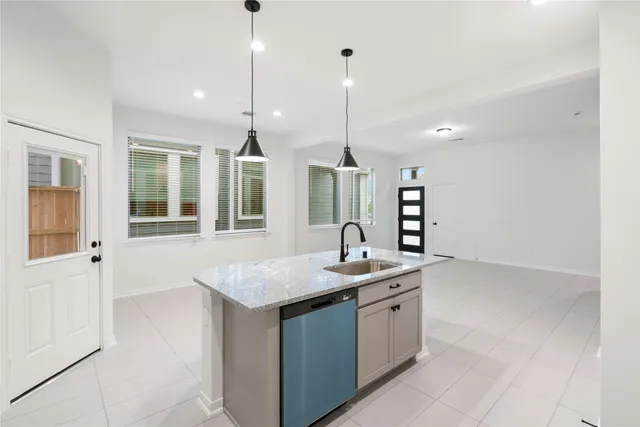 a kitchen with a sink chandelier and living room view