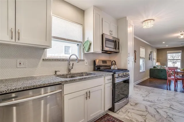 a kitchen with stainless steel appliances granite countertop a stove a sink and a microwave