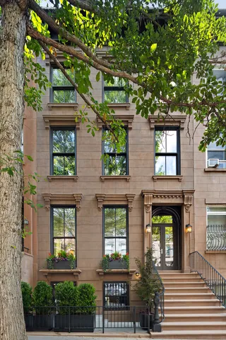 a front view of a residential apartment building with a tree