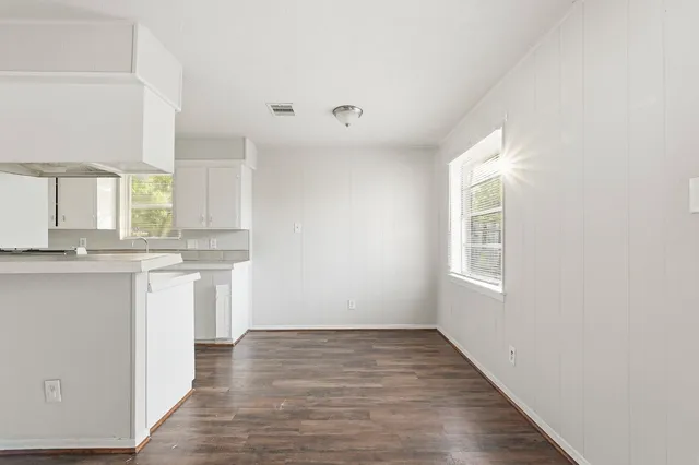 a view of a kitchen with granite countertop white cabinets and wooden floor