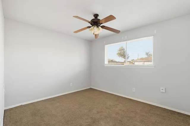 an empty room with window and ceiling fan