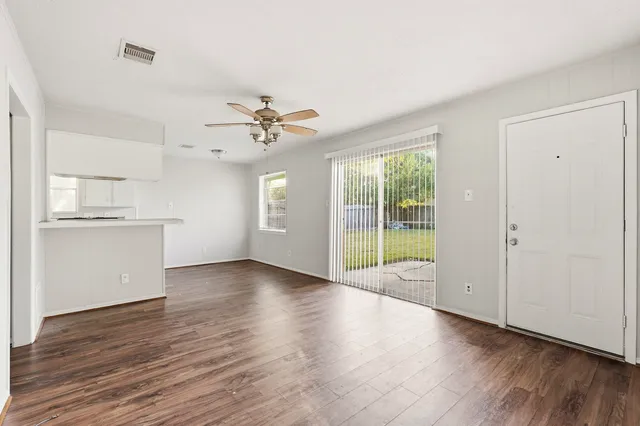 a view of an empty room with a window and wooden floor