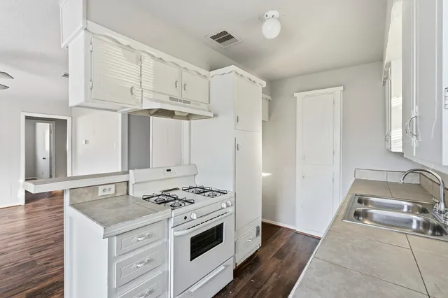 a kitchen with granite countertop a sink a stove and a wooden floors