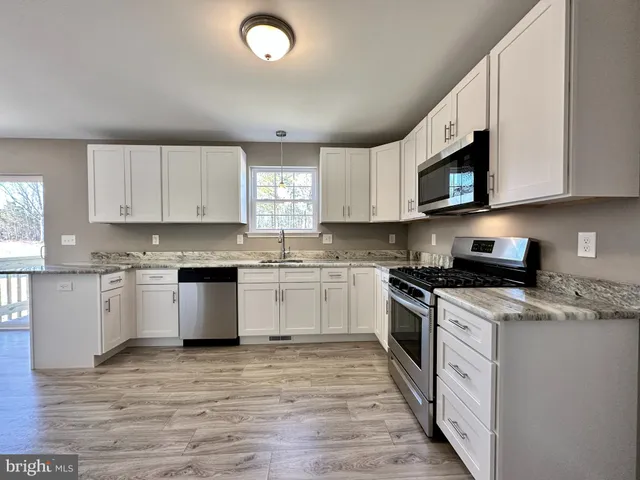 a kitchen with stainless steel appliances granite countertop a stove a sink and a microwave