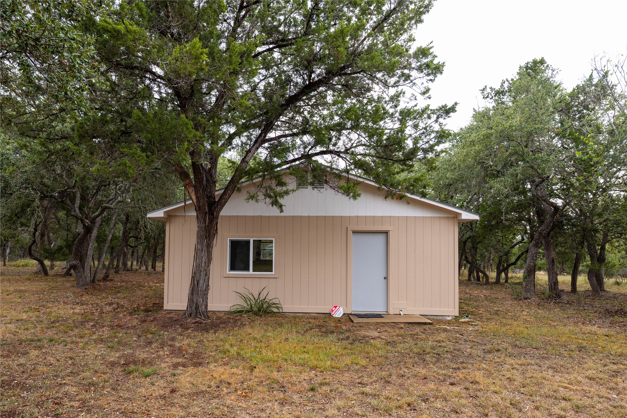 2501 Fischer Store Road Wimberley, TX 78676 - Photo 13 of 23 Exterior structure featuring neutral-toned vertical siding, a white trim, and a gray entry door