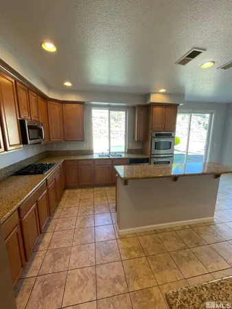 a large kitchen with granite countertop a stove a sink and a microwave
