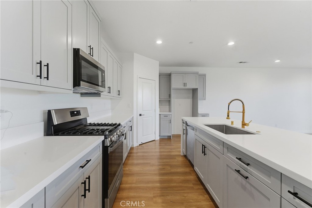 10710 Brookfield Drive Riverside, CA 92505 - Photo 11 of 32 a view of a kitchen with a sink and dishwasher a stove top oven with wooden floor