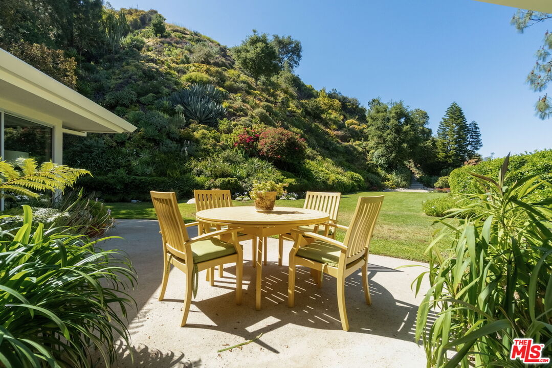 a patio with table and chairs and potted plants