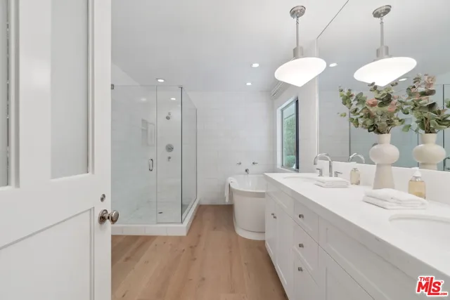 a spacious bathroom with a double vanity sink a large mirror and a shower