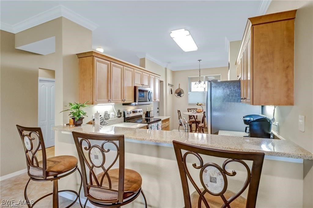 8261 Pathfinder Loop, Unit 745 Fort Myers, FL 33919 - Photo 4 of 22 a kitchen with stainless steel appliances granite countertop a table chairs in it and wooden floors