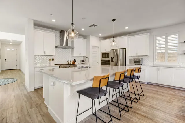 a kitchen with stainless steel appliances kitchen island granite countertop a stove a sink and a refrigerator