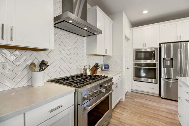 a kitchen with stainless steel appliances a dining table chairs and wooden floor