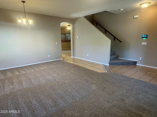 a view of an empty room with a chandelier fan
