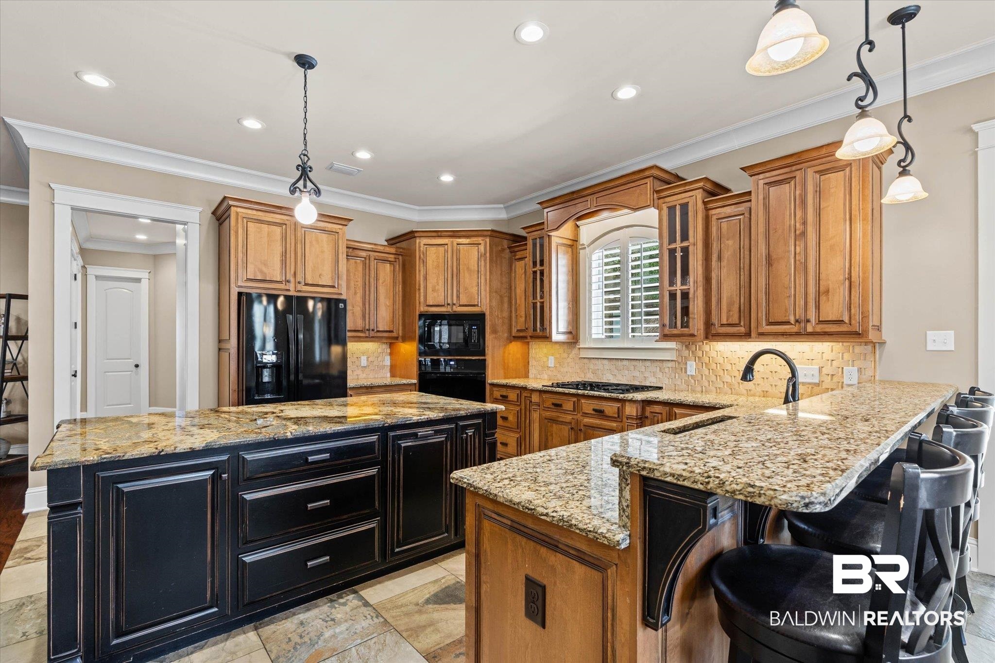 7676 Rockstone Lane Mobile, AL 36695 - Photo 11 of 47 Dual tone kitchen featuring light stone countertops, glass insert cabinets, hanging light fixtures, dual tone cabinets, and crown molding