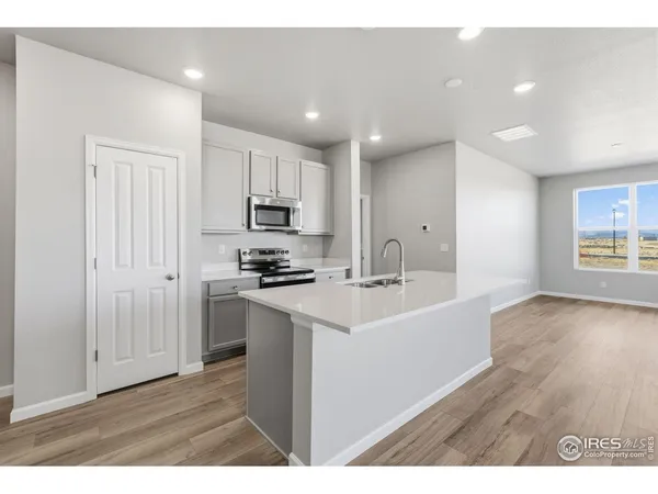 a large white kitchen with wooden floor