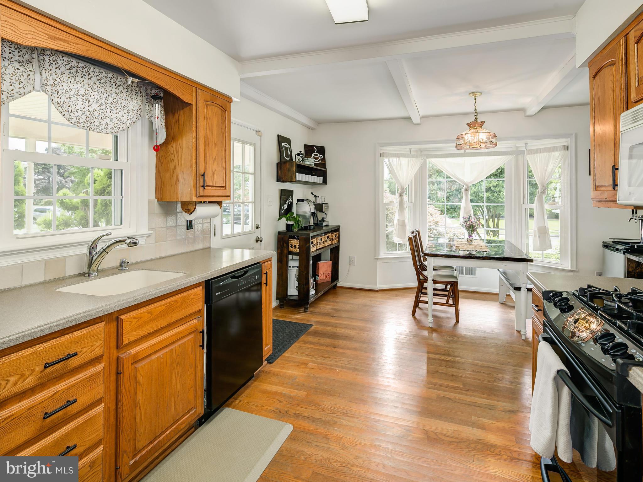 199 Summit Hall Road Gaithersburg, MD 20877 - Photo 8 of 30 a large kitchen with stainless steel appliances granite countertop a stove a sink dishwasher a dining table and chair with wooden floor