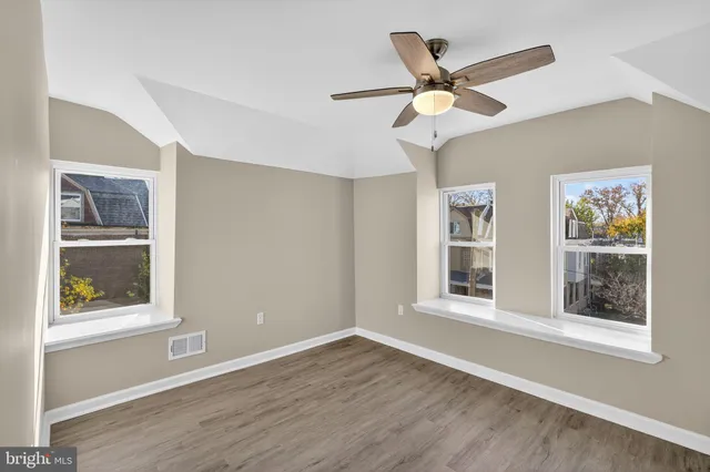 a view of an empty room with a window and wooden floor