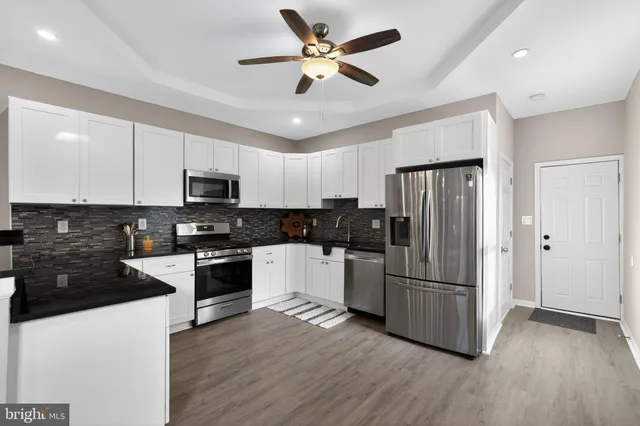 a kitchen with granite countertop a refrigerator a stove a sink and white cabinets
