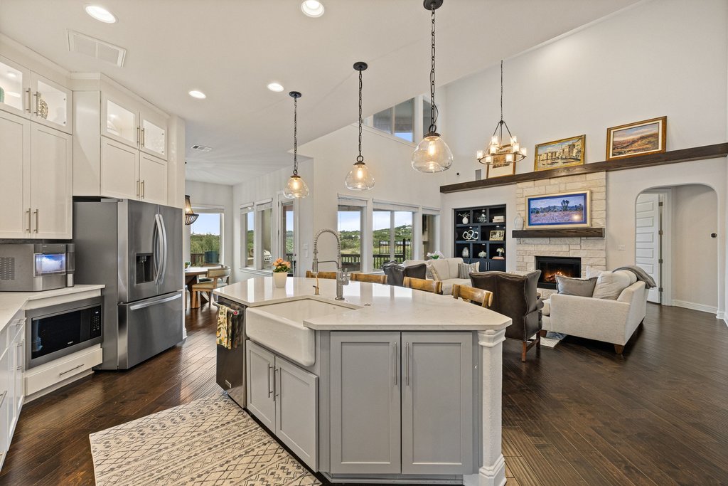 215 Lodestone Lane Austin, TX 78738 - Photo 4 of 40 An open concept living area boasts a modern kitchen island with a farmhouse sink and hardwood floors.
