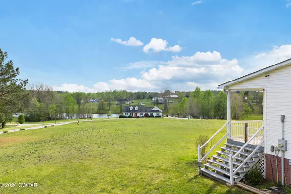 a view of a big yard with swimming pool and trees