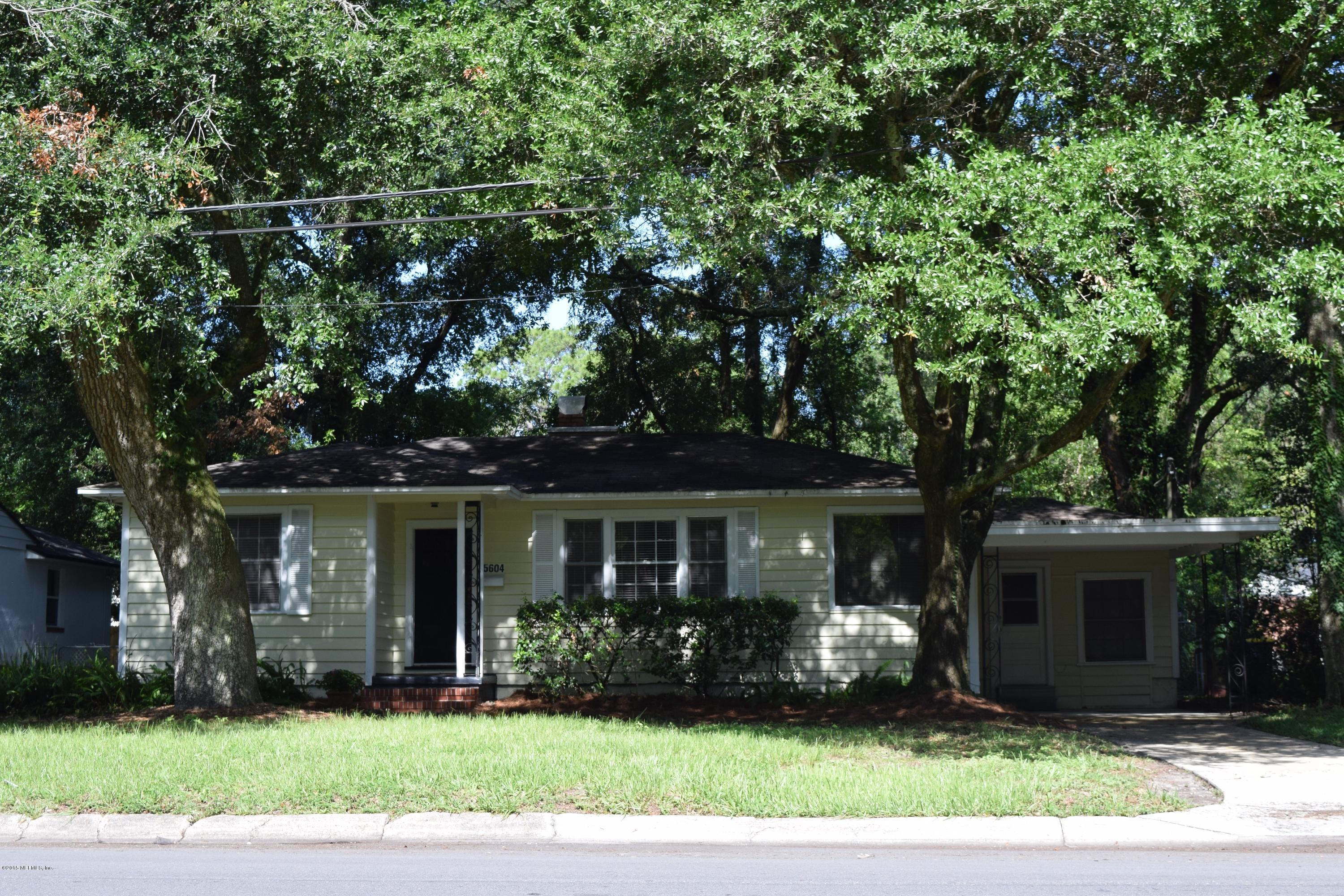 a front view of a house with a yard and potted plants