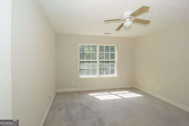 an empty room with a window and ceiling fan