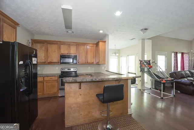a kitchen with stainless steel appliances granite countertop a refrigerator a stove top oven a sink dishwasher and wooden cabinets with wooden floor