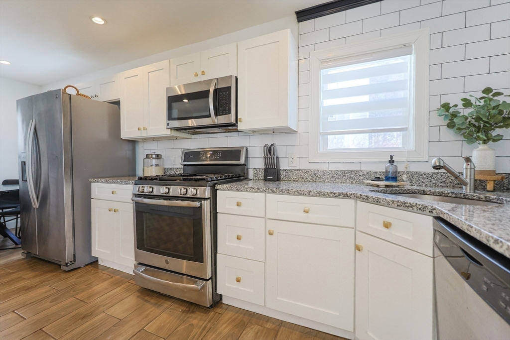 251 High Street Webster, MA 01570 - Photo 21 of 38 a kitchen with granite countertop white cabinets stainless steel appliances and a window