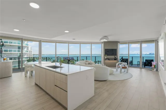 a large white kitchen with a large window and table