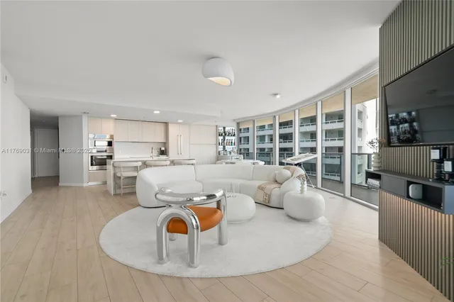 a living room with furniture kitchen view and a large window