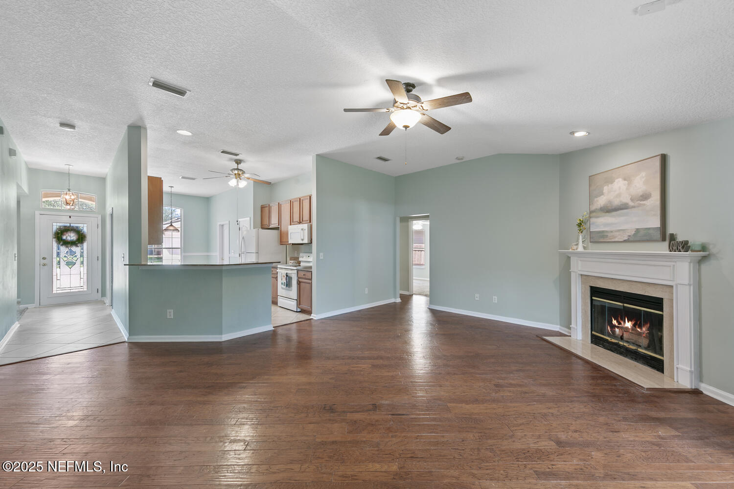 9317 Beresford Court Jacksonville, FL 32244 - Photo 12 of 55 a view of a livingroom with a fireplace a chandelier and wooden floor