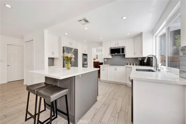 a kitchen with stainless steel appliances a kitchen island hardwood floor sink stove dining table and chairs