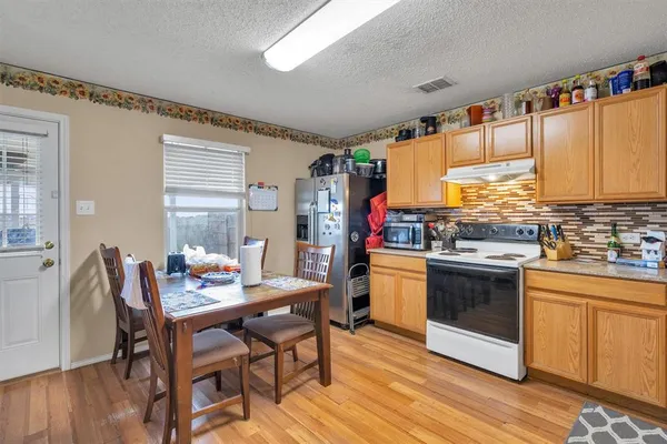 a kitchen with stainless steel appliances kitchen island granite countertop a table chairs sink and cabinets