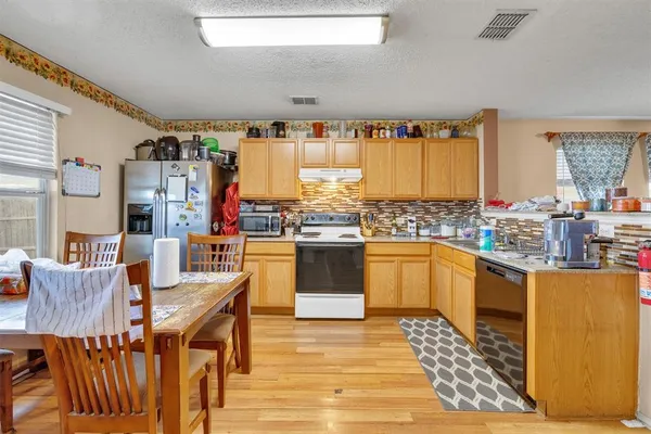 a kitchen with stainless steel appliances kitchen island granite countertop a table chairs in it and a wooden floor