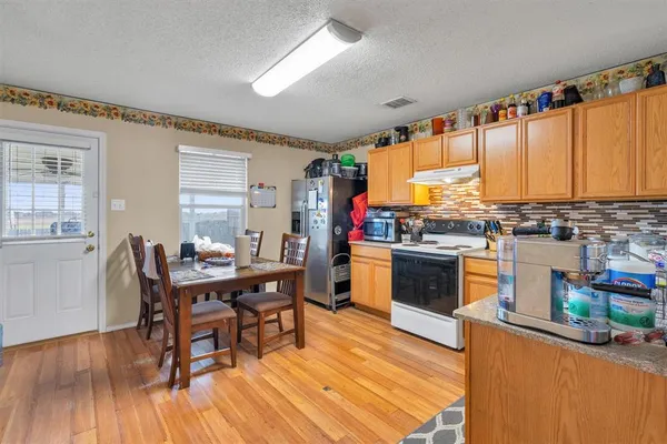 a kitchen with stainless steel appliances a stove a sink dishwasher and a dining table with wooden floor