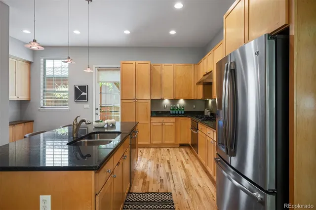 a kitchen with kitchen island granite countertop a sink refrigerator and cabinets