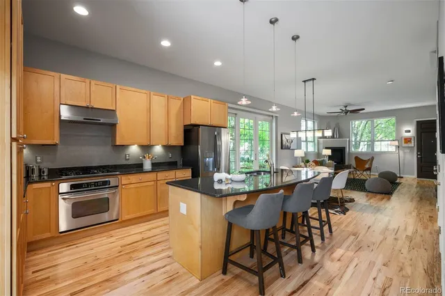 a kitchen with stainless steel appliances granite countertop wooden floor a stove a sink dishwasher and a refrigerator with wooden floor