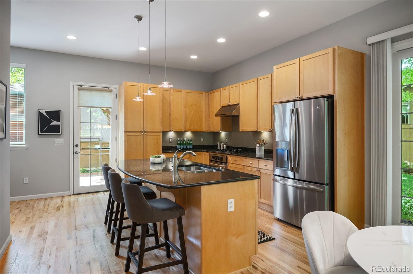 217 Spruce Street, Unit 101 Denver, CO 80230 - Photo 9 of 37 a kitchen with stainless steel appliances granite countertop a refrigerator a stove a sink a dining table and chairs with wooden floor