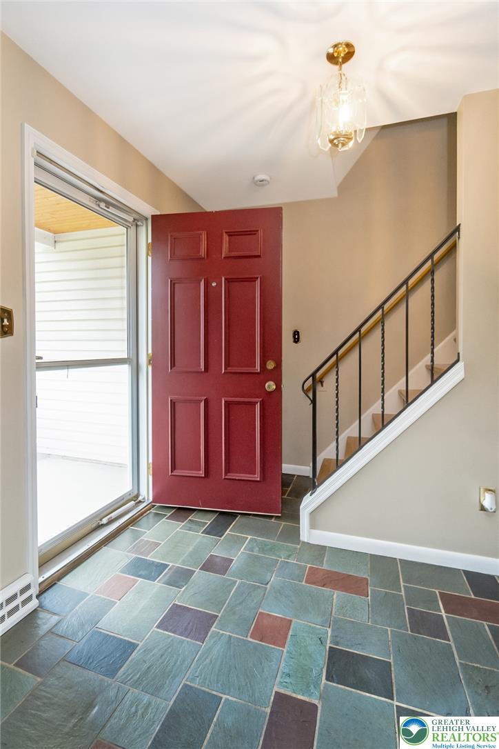 268 Apollo Drive Bethlehem, PA 18017 - Photo 4 of 56 A vibrant red entry door welcomes you into a home featuring multicolored flagstone flooring and a classic staircase.