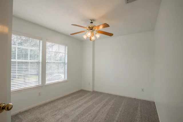 an empty room with a window and a fan