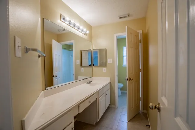 a spacious bathroom with a double vanity sink a large mirror and shower