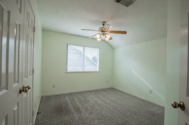 an empty room with windows and fan