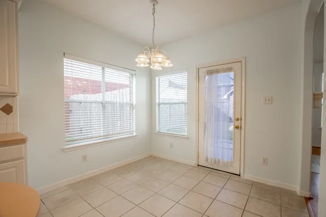 a view of an empty room with window and chandelier