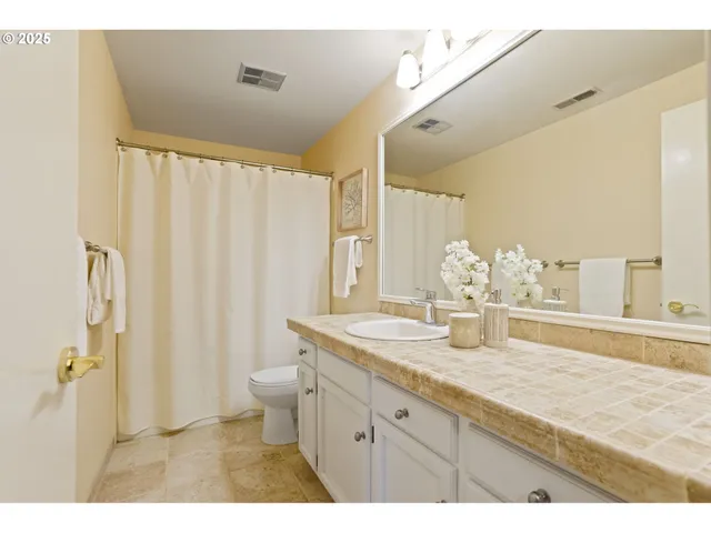 a bathroom with a granite countertop sink a toilet a mirror and shower