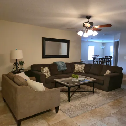 a living room with furniture a light fixture and a ceiling fan