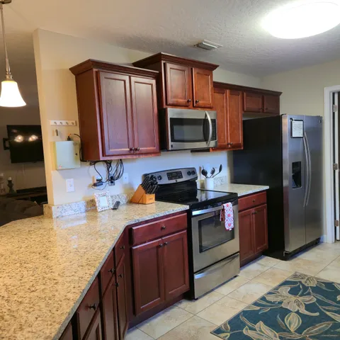 a kitchen with granite countertop stainless steel appliances microwave stove refrigerator and sink