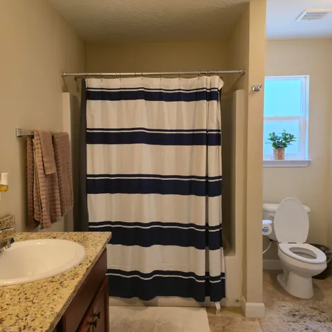 a bathroom with a granite countertop sink and a toilet